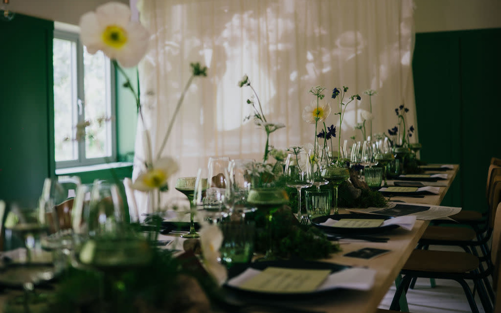 Autumnal flowers sit in the centre of a wedding table surrounded by candles and glassware