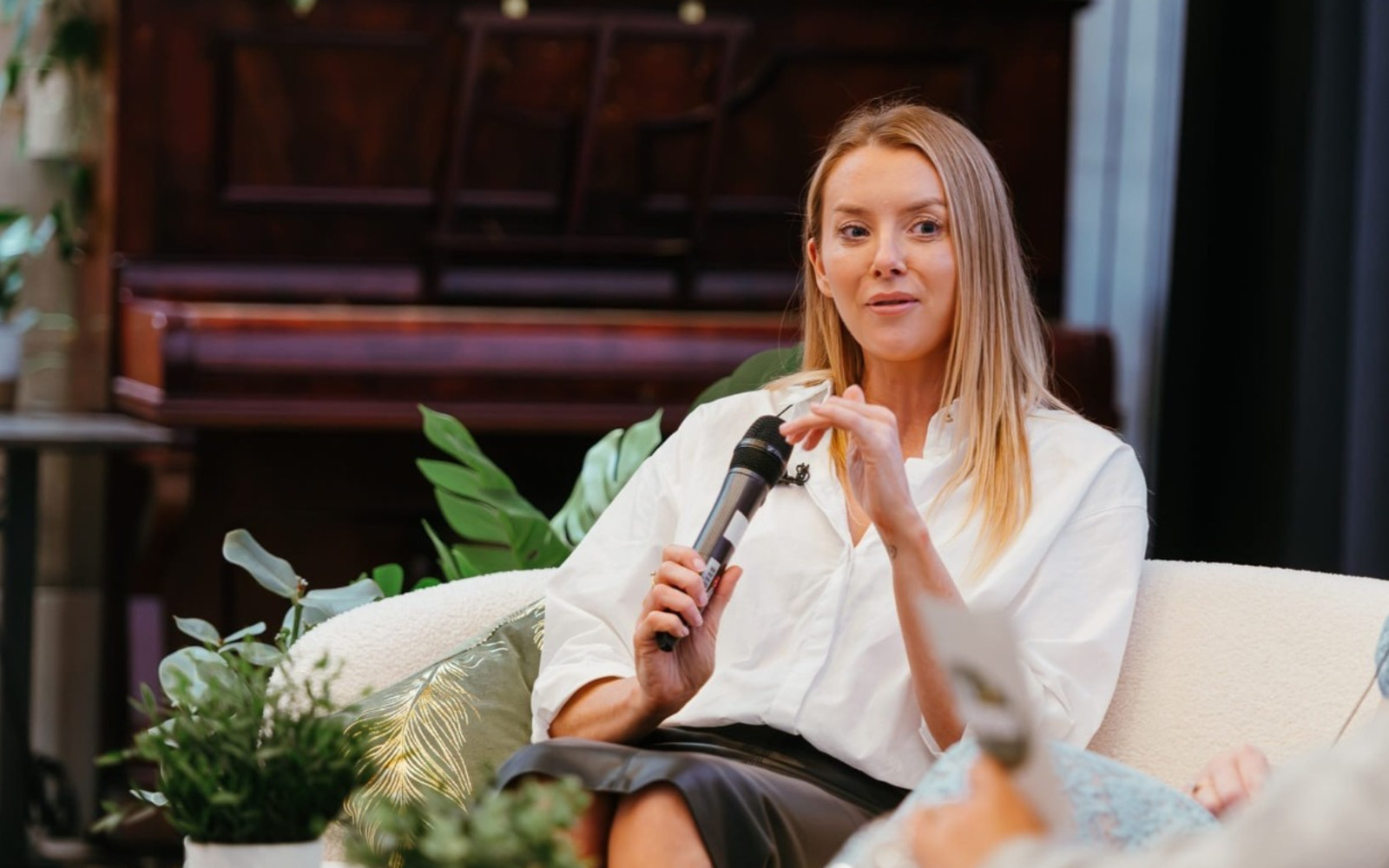 Picture of Jen Healy holding on a microphone on a couch
