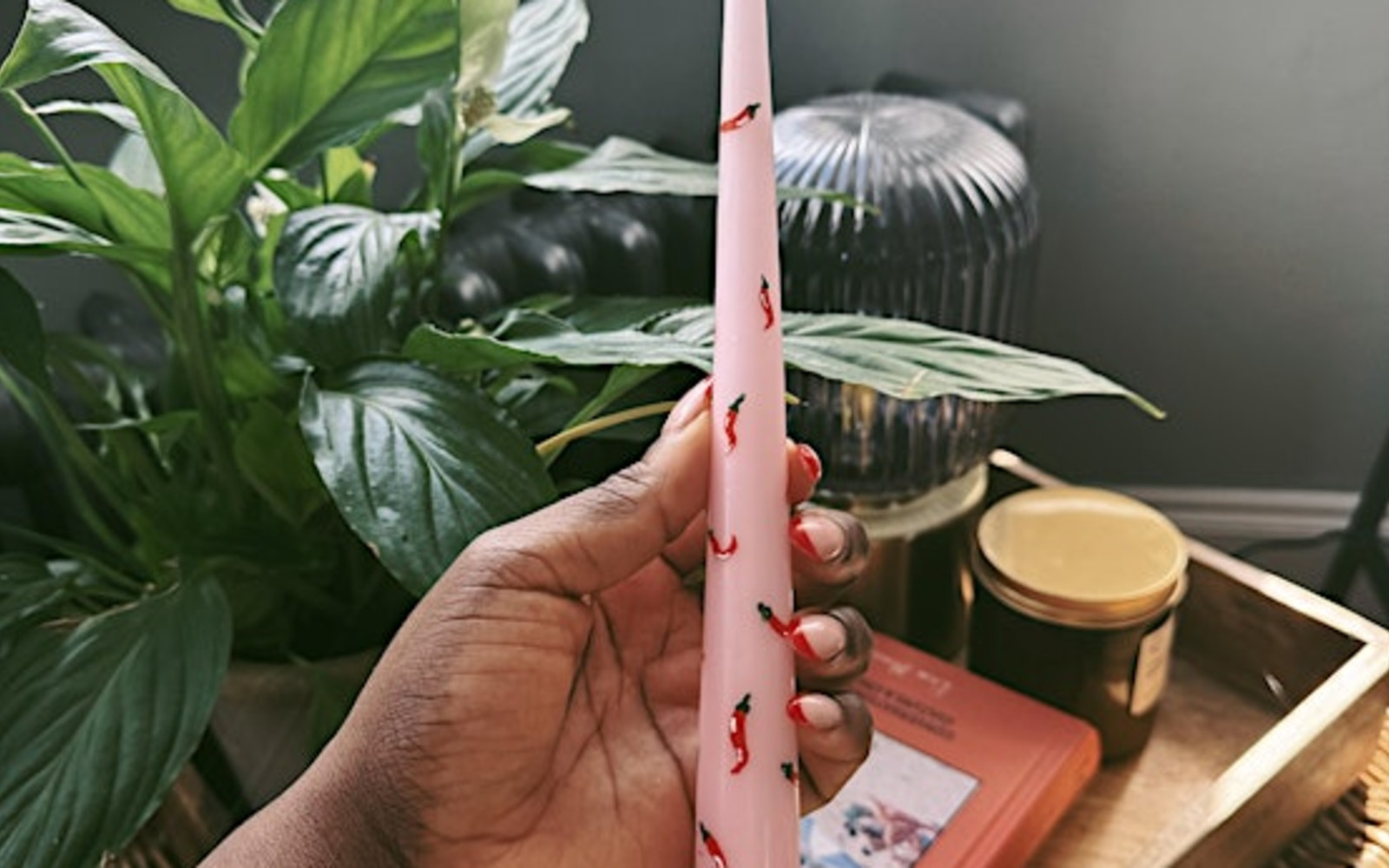 Woman holding a pink taper candle with chili's painted on