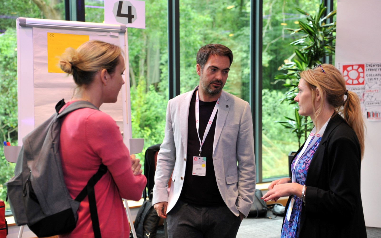Three attendees talking in a group next to a flipchart