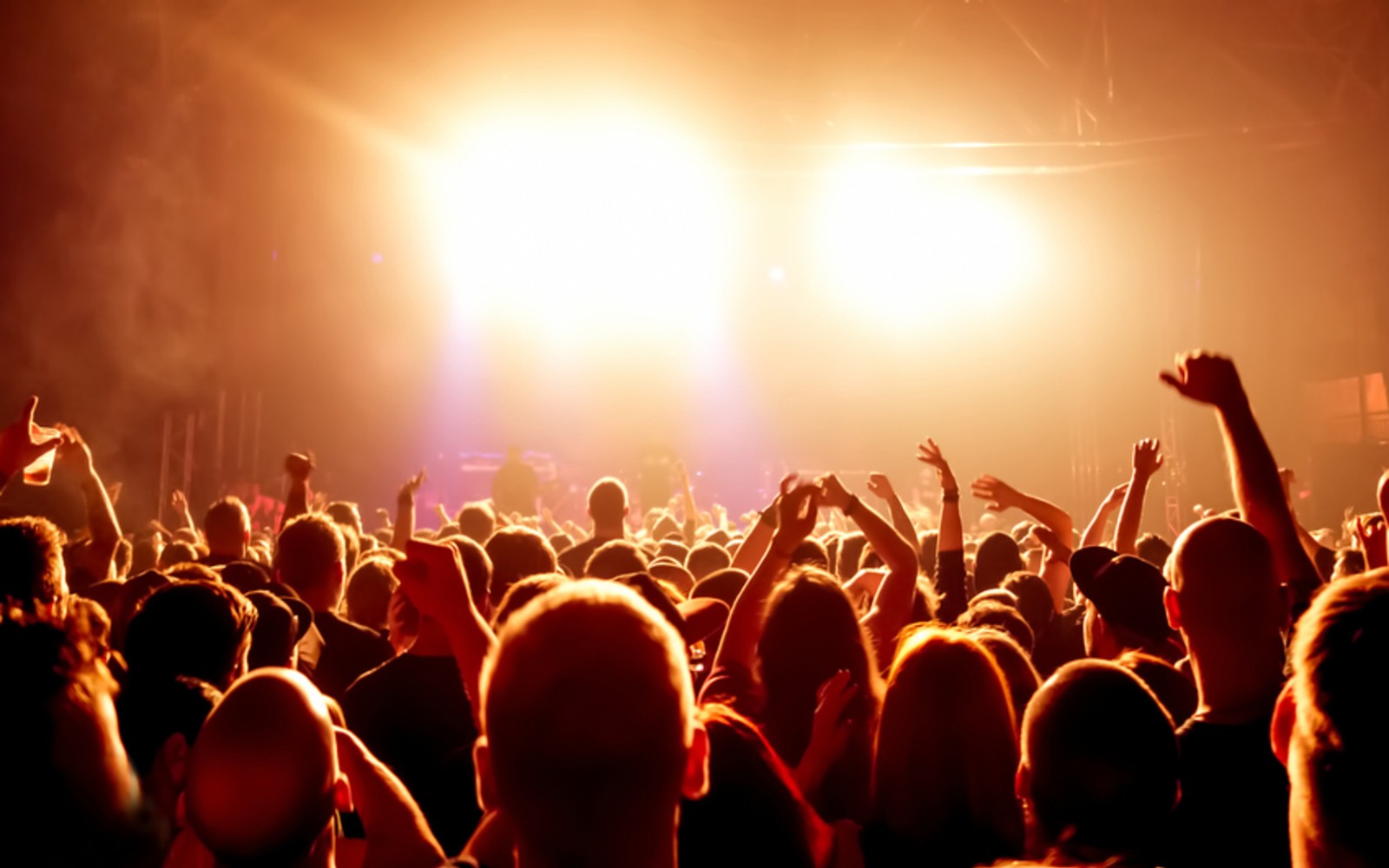 Group of people at a concert looking towards the bright lights of the stage