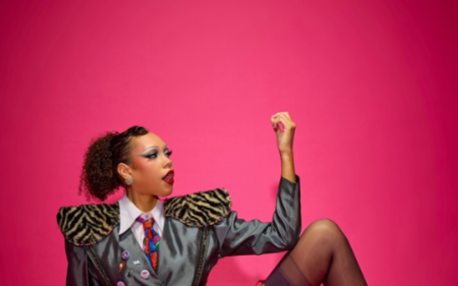 Photo is of Dawn Voz sitting and looking up towards a lifted arm. Photographed by Ralph Barklam.