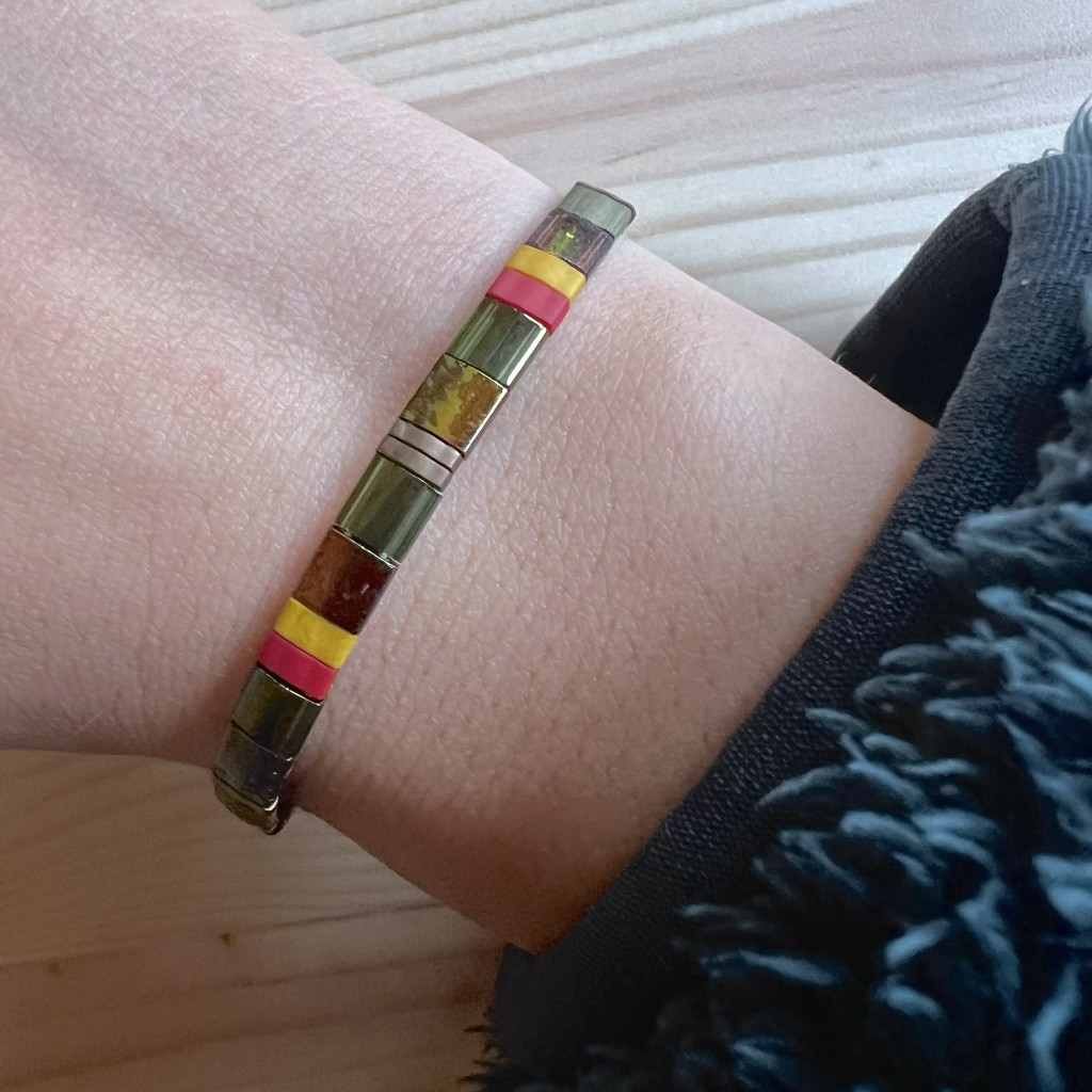 A stack of 4 colourful beaded bracelets. The beads are square-shaped and are in various colours of blue, green, orange, pink and purple.
