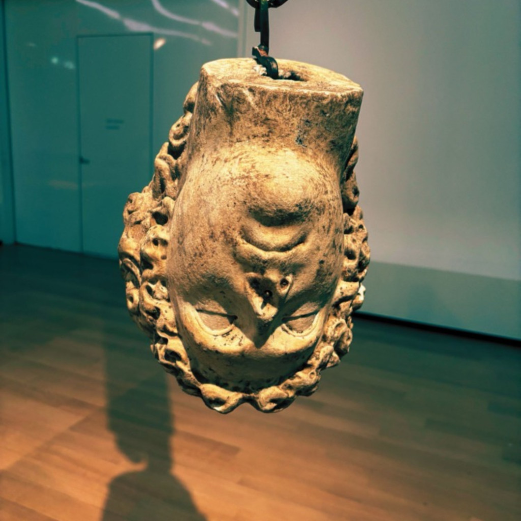 A marble statue's head hung upside down by a hook.