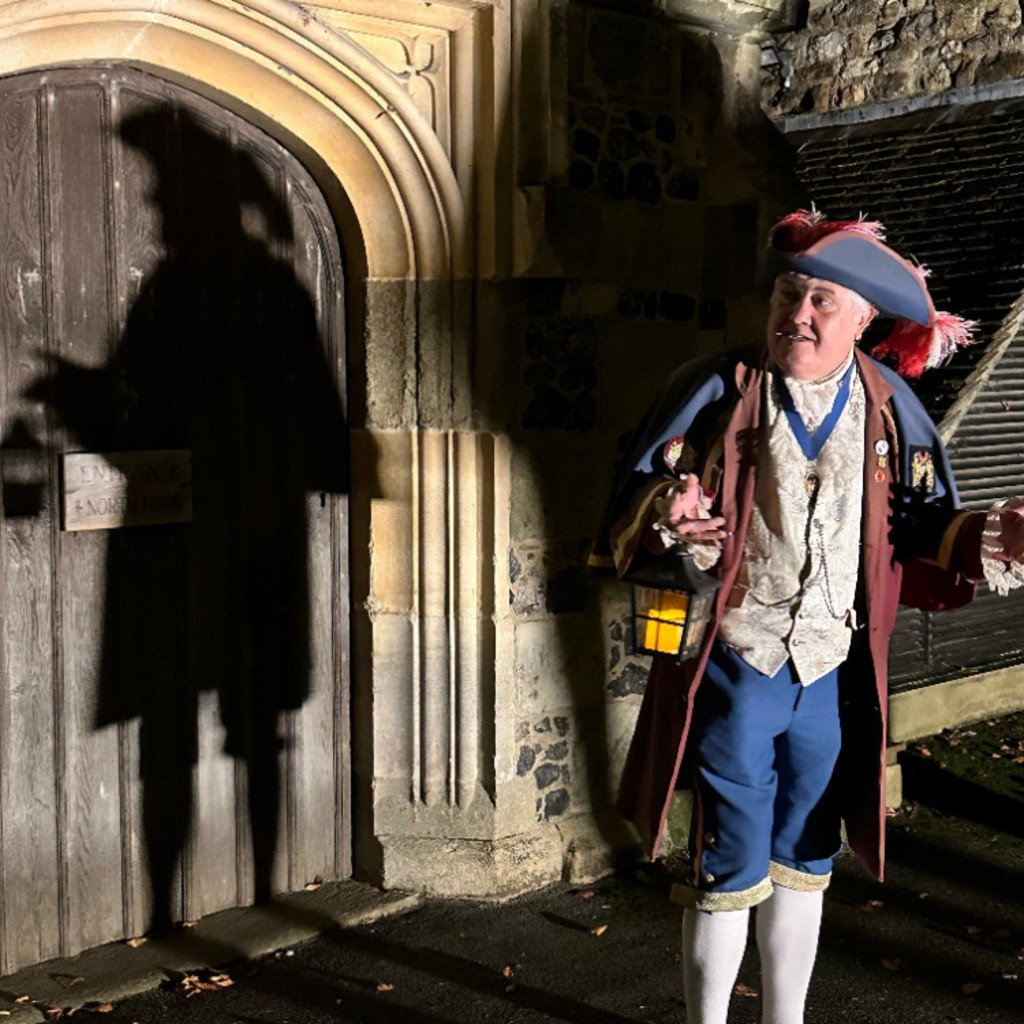 The Town Crier of Rye holding a lamp in front of a Church door