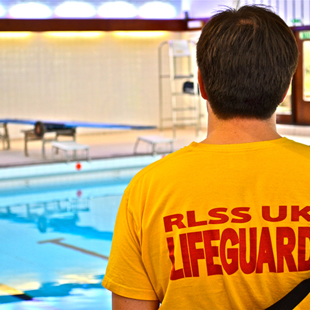 Rear view of a male Lifeguard on poolside