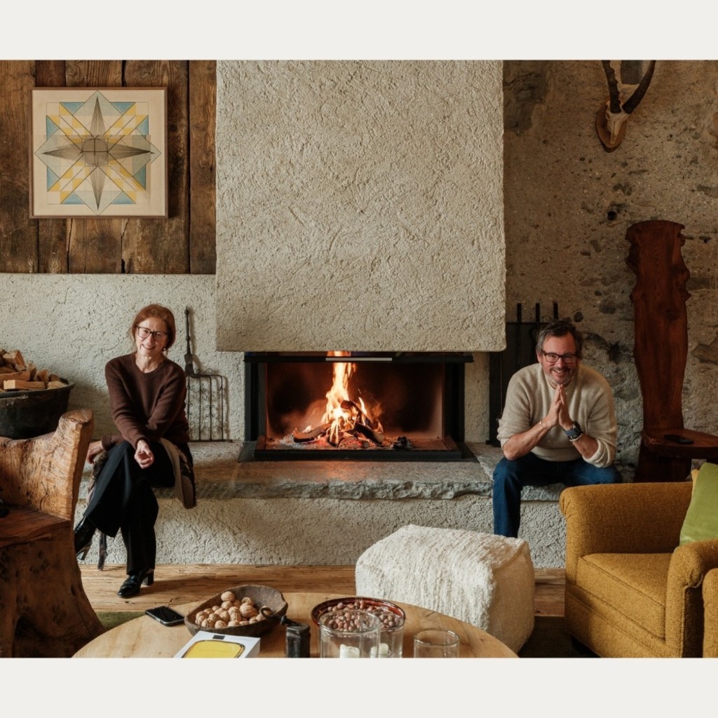 A man and woman sitting either side of a modern fireplace.