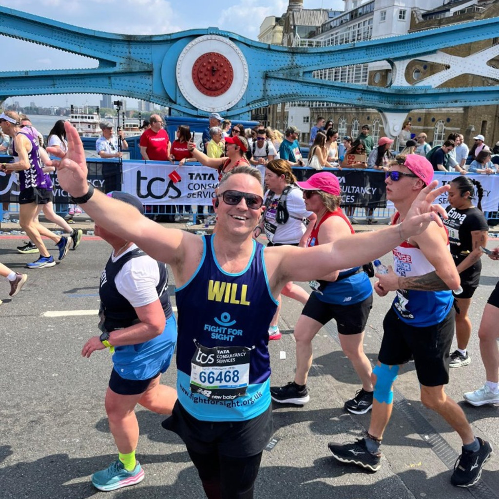 A Fight for Sight supporter waving whilst running across Tower Bridge in the London Marathon