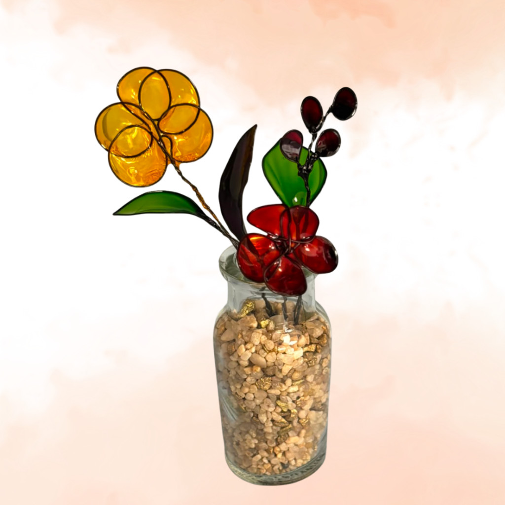 Glass bottle full of small stones with a bouquet of a yellow, red and purple wire shaped flowers and leaves dipped in resin