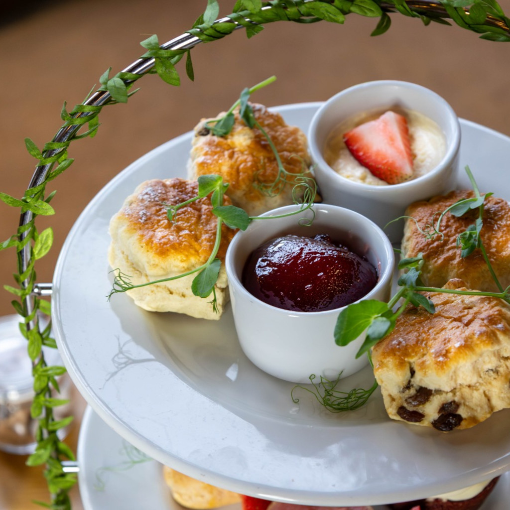 Scones, strawberry jam and cream on the top of an afternoon tea stand.