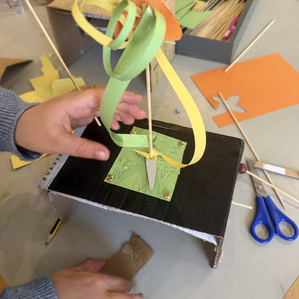 Image shows a child making a cardboard automaton in the shape of a daffodil