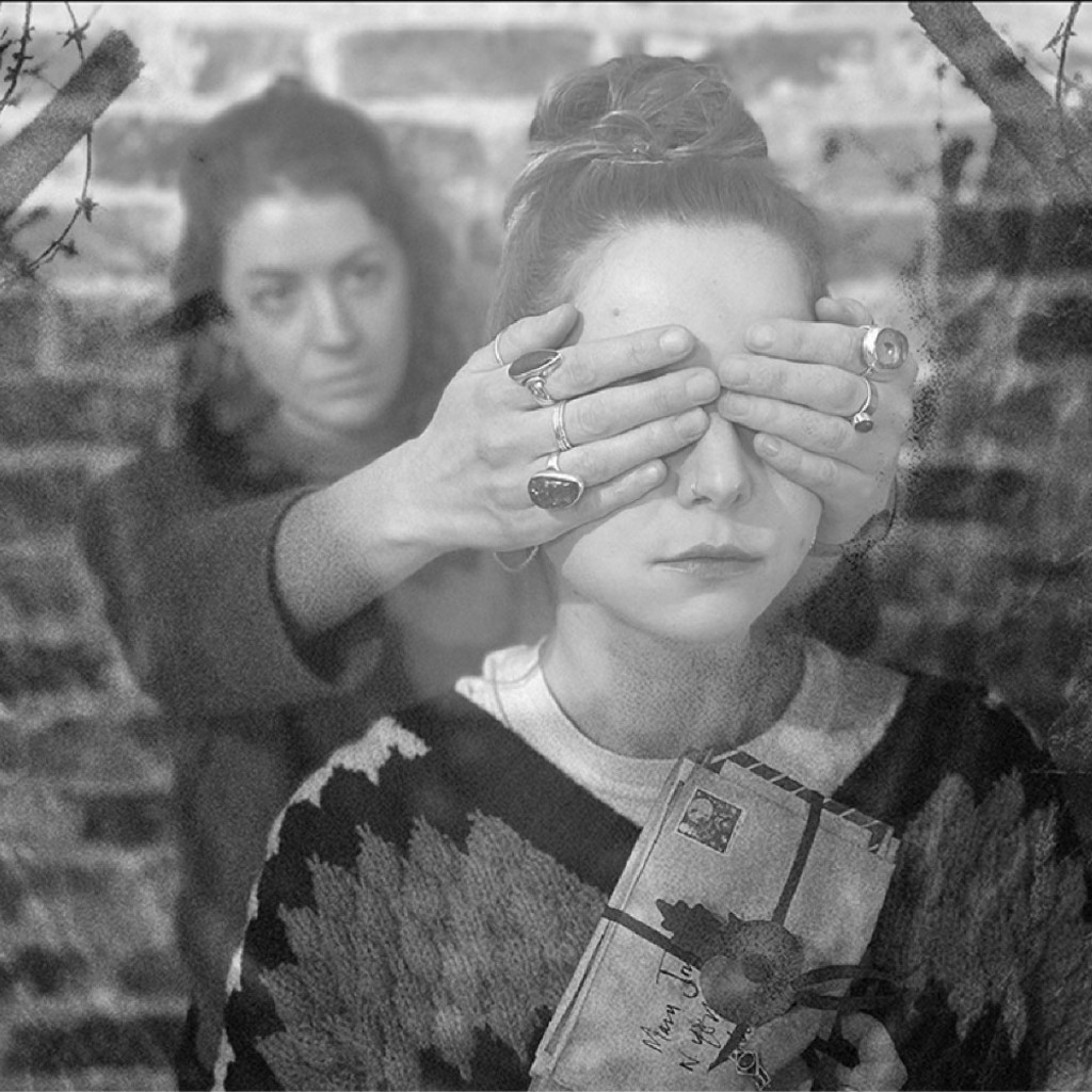 A girl holding a bundle of letters with hands over her eyes