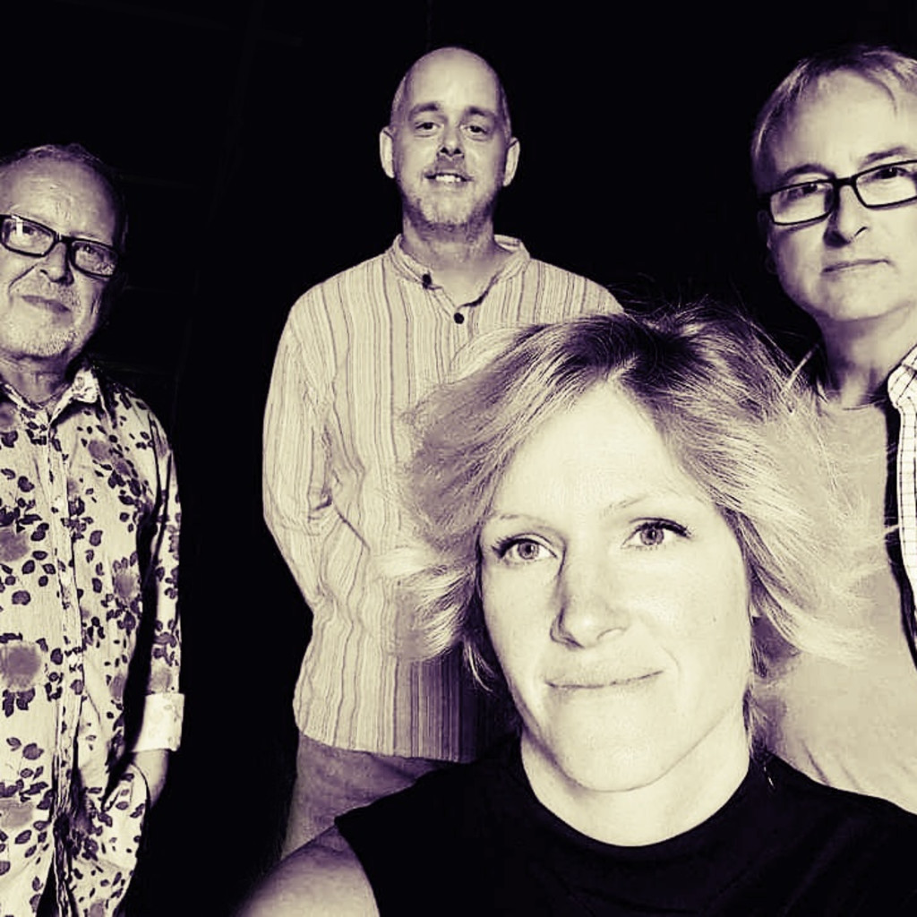 Four adults pictured in black and white, posing for a selfie.