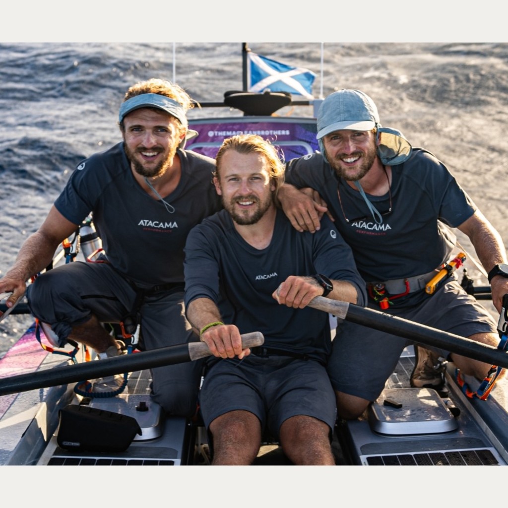 Three men in a rowing boat with a Scottish flag.