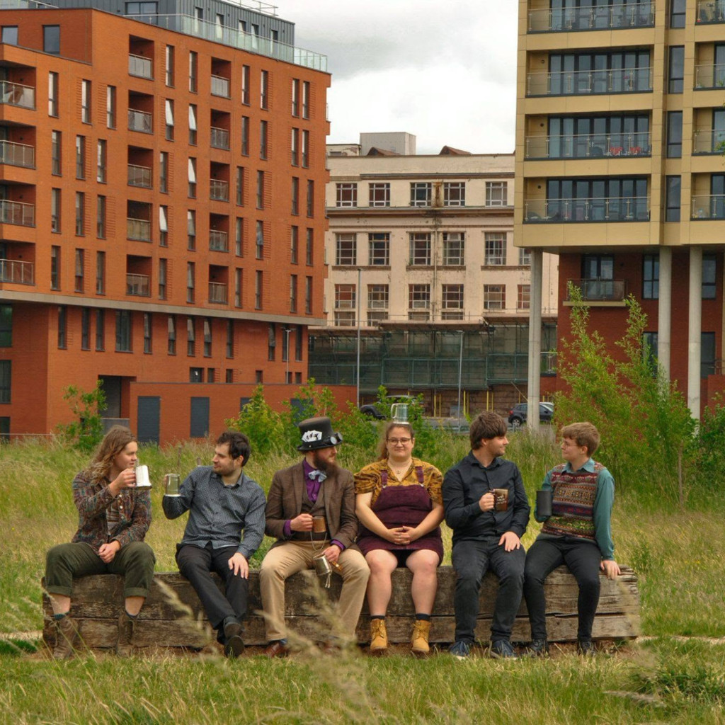 The image features Chimera sat in front of buildings, looking at each other and holding mugs in various poses