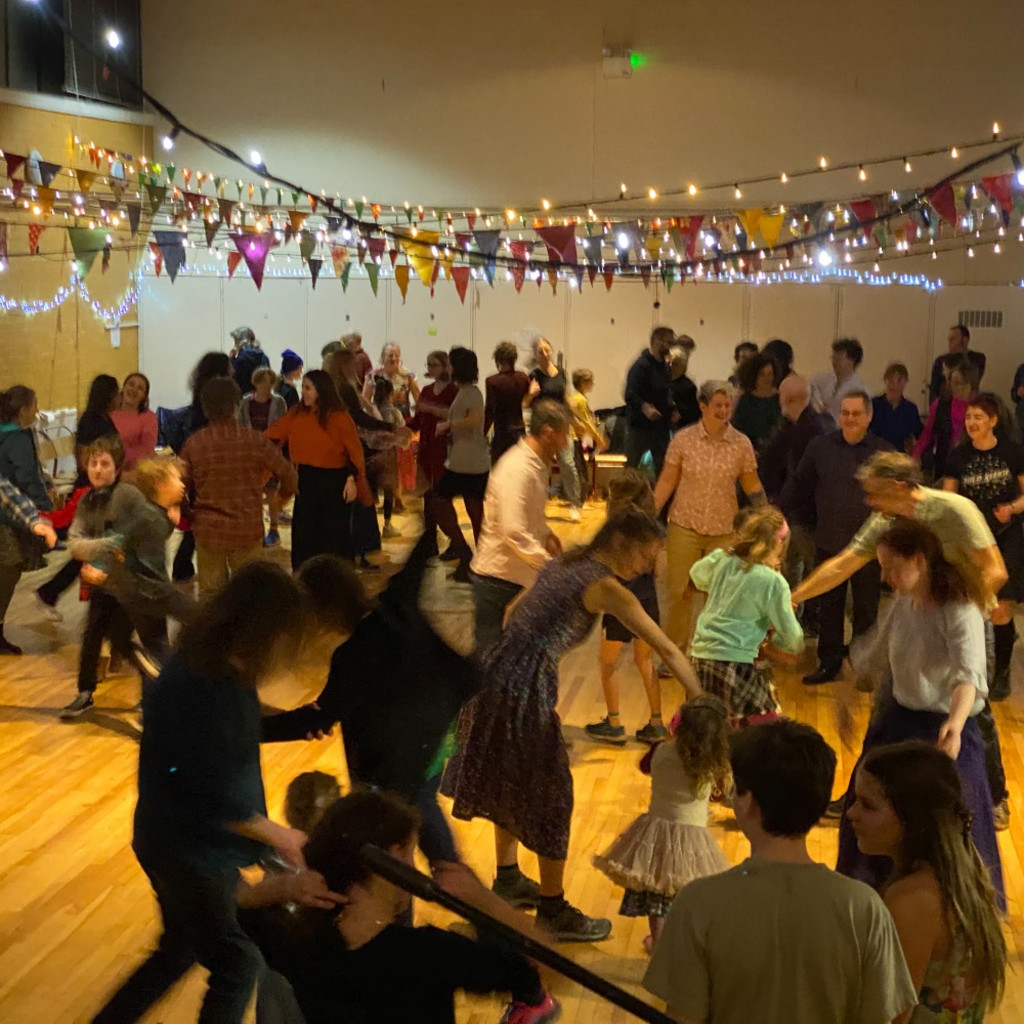 Lots of people dancing under rope lighting and colourful bunting