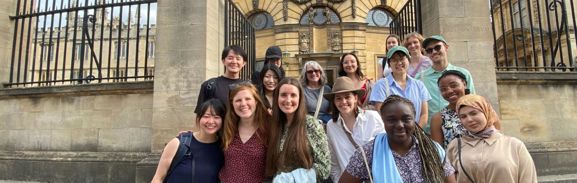 Woman standing with a tote bag next to a group of walking tour attendees next to Baliol College