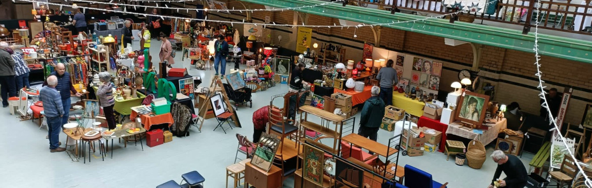 Tiled Swimming Pool Floor, People Looking around at stalls. Furniture, Rugs, Art is displayed