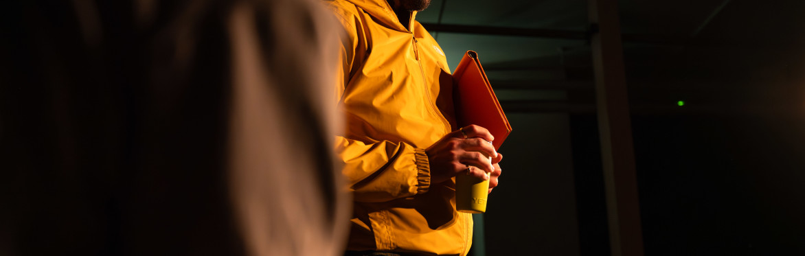 Two men shake hands across a small table during a performance of The Borrowed Room.