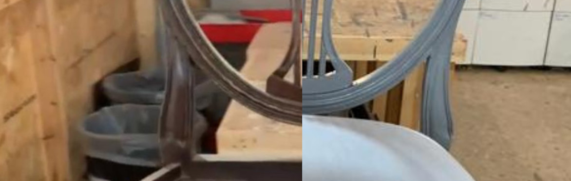 2 people are in a workshop setting, the one on the right is directing the other person how to upholster a dining chair seat with black fabric, using an air powered staple gun.