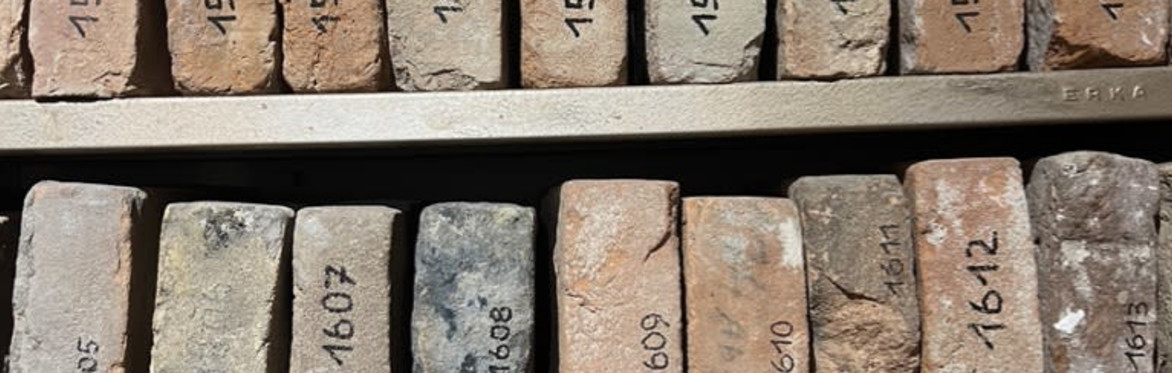 Ein Hauseingang, der beton in ocker und grau gestrichen, links eine Lampe ohne Lampenschirm
