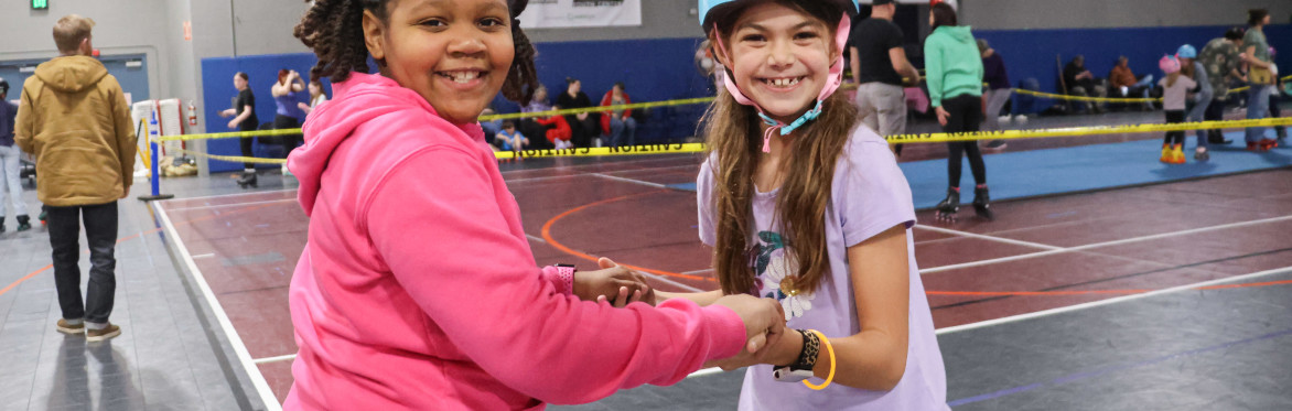 Two friends hold hands while skating