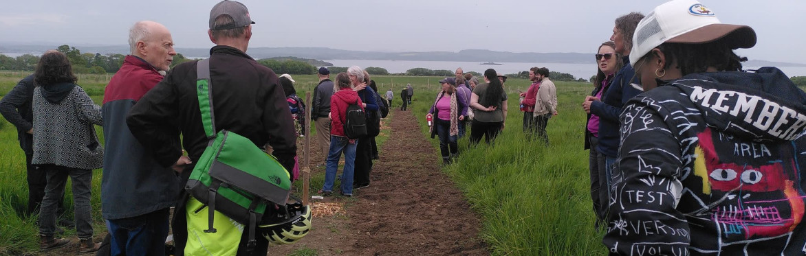 Smiling people dressed warmly and gathered in a group in the fields of Lauriston Farm