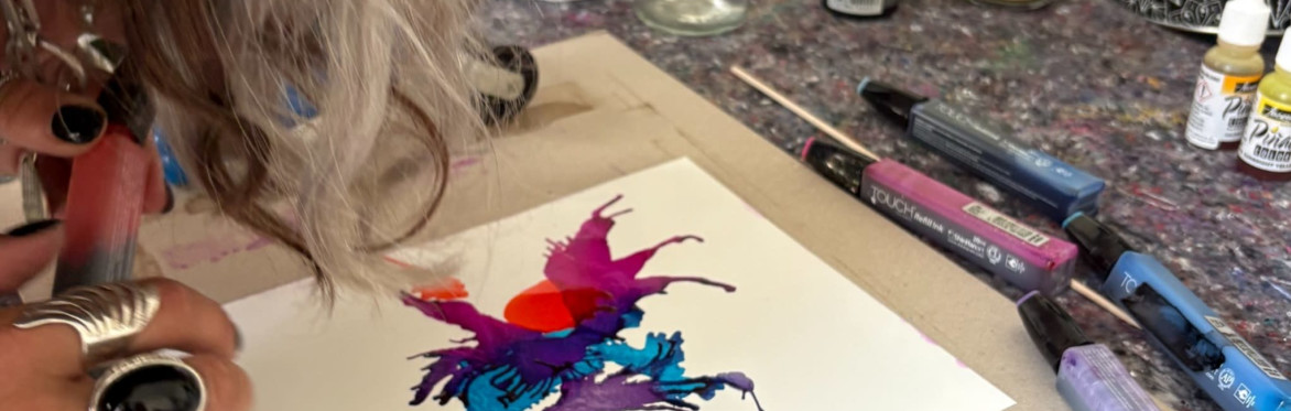 Two participants creating colorful alcohol ink artworks in a bright artist studio.
