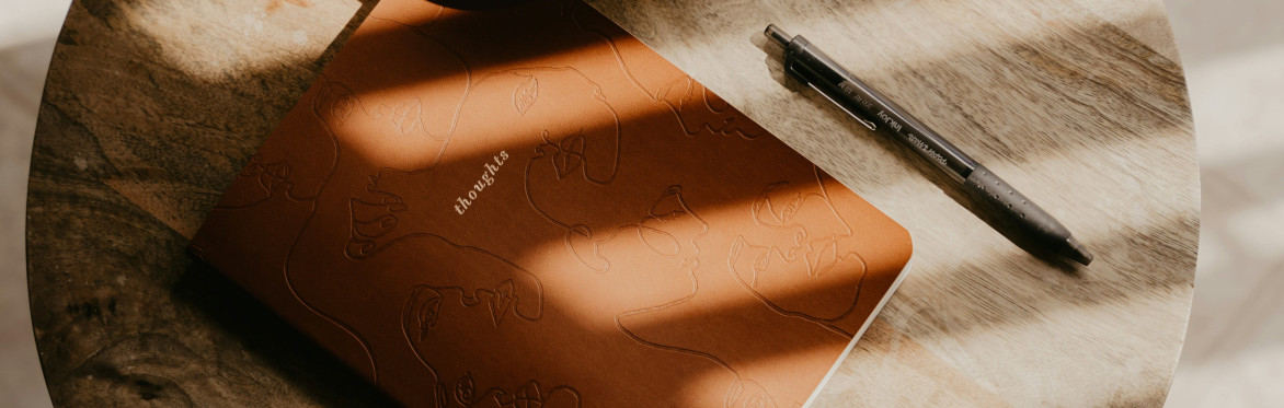 A handwritten note pad with a fountain pen sat on top