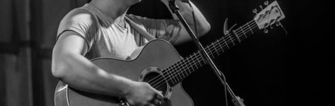 Sam looking down on his guitar onstage