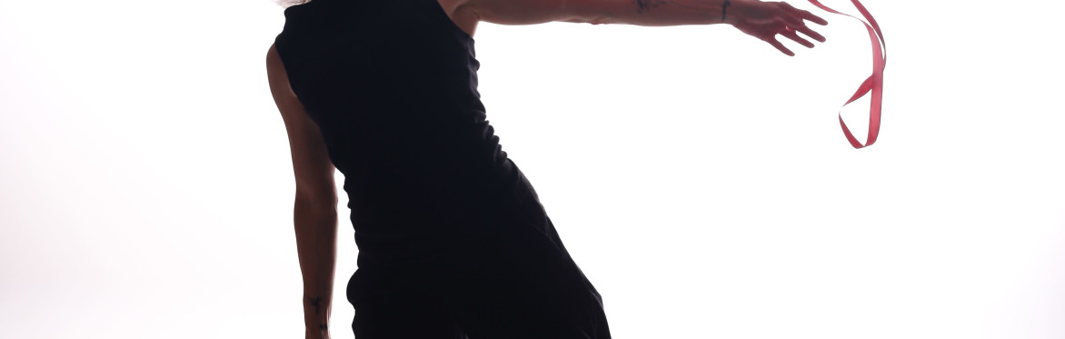 Dancer dressed in black, reaching to left