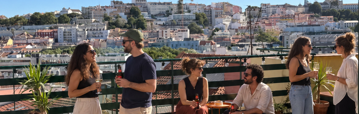 People standing on a rooftop during a Creative Playground Night, having a drink with a view over Lisbon.