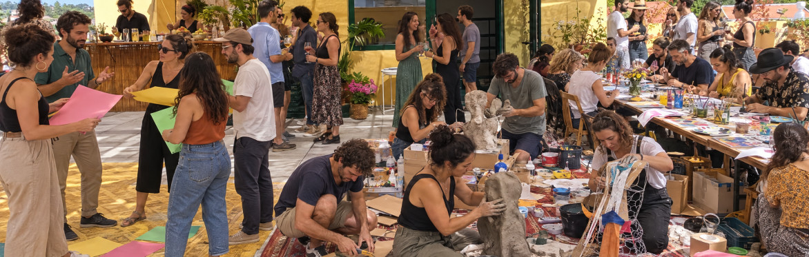 A big group of people on a rooftop involved in various creative activities during a Creative Playground Night.