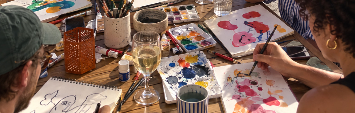 a table full of drawings, paintings, water and acrylic colors and people painting pictures.
