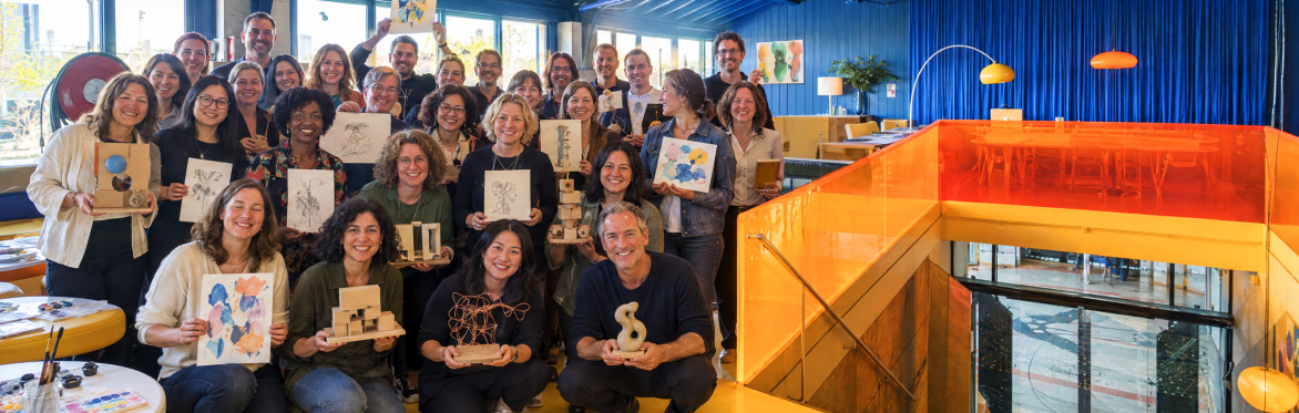 A group of people holding up their artistic creations after a Creative Playground Night.