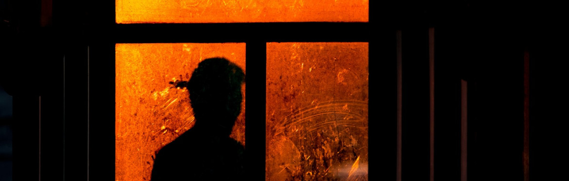 a figure in silhouette against an orange-lit window