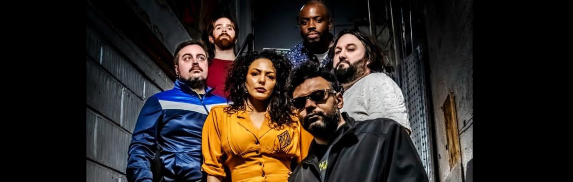 Kiziah and the Kings, a 6 piece band, stood on steps in a stairwell,  not smiling