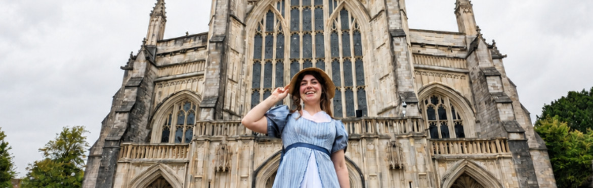 Miss Deane smiling in front of the grand west entrance of Winchester Cathedral.