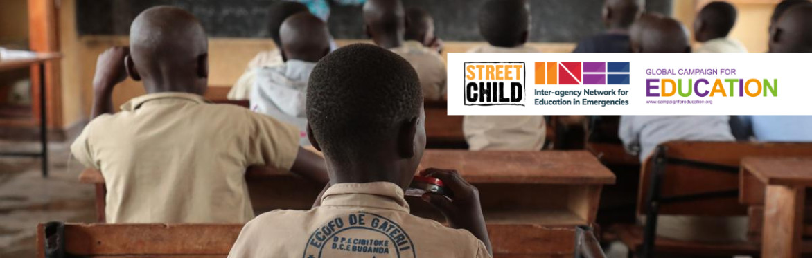 Children sitting in class paying attention to the chalkboard. Image taken from the back of the classroom