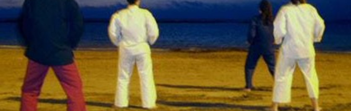 People practising Tai Chi on the beach