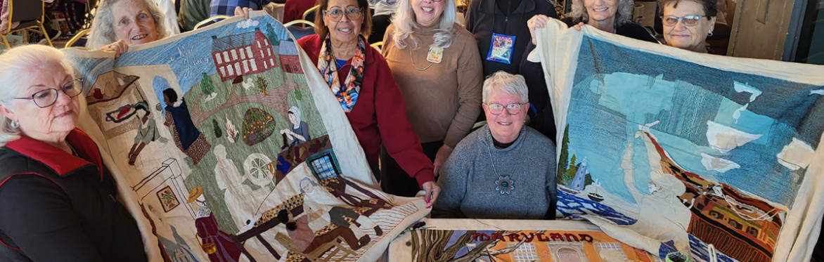 Women gather around two of the tapestry panels from America's tapestry