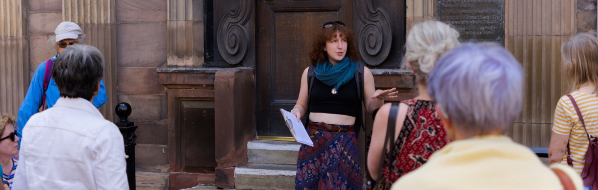 A photograph showing a tour guide talking to a group of people