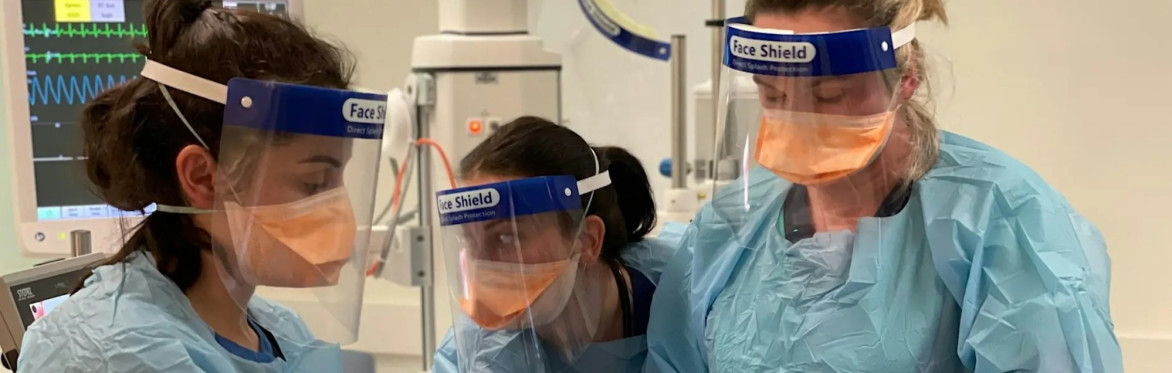 Three clinicians in PPE performing an airway procedure during resuscitation training