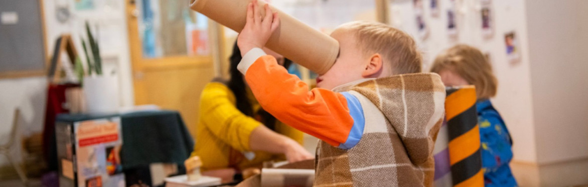 Child looks upward through a paper tube
