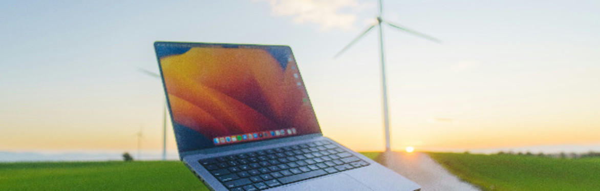 A person is holding a laptop in the middle of a road in front of a wind turbine - Photo by Zac Wolff on Unsplash