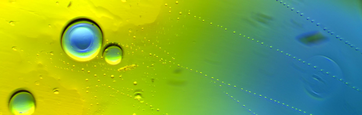 An image of yellow, green and blue dyes on a plate under a microscope, with droplets and traces of dye in a gradient of colour.