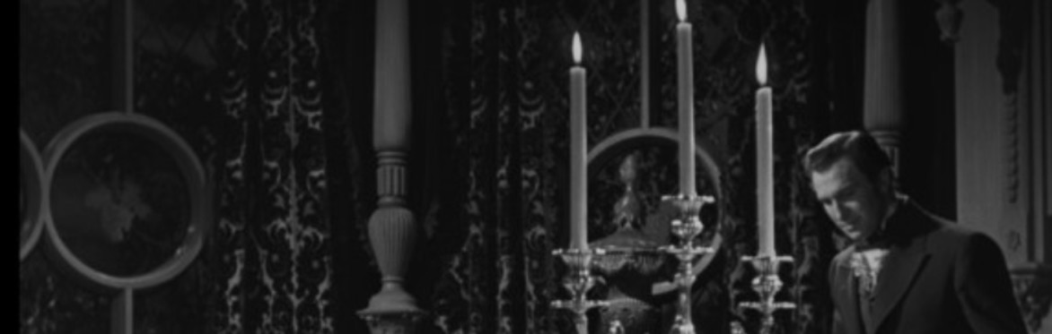 A man loitering by a table and a massive candlestick