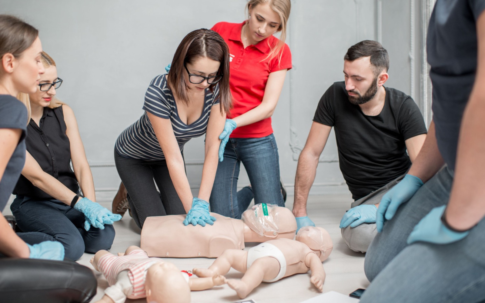 People doing chest compressions on a maniquin