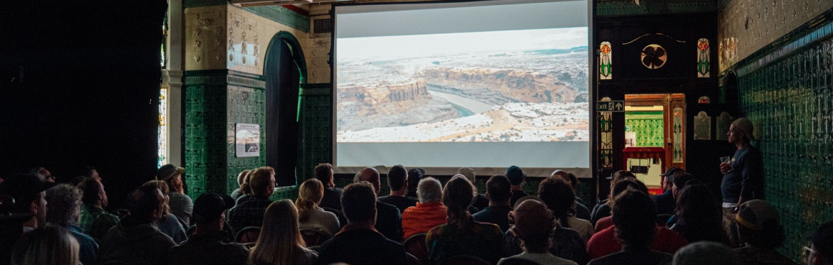 A group of people watching a cycling film in an ad-hoc cinema set up
