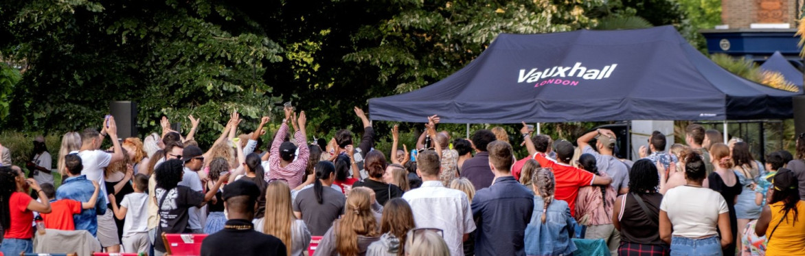 A crowd watches an outdoor music event in a park.